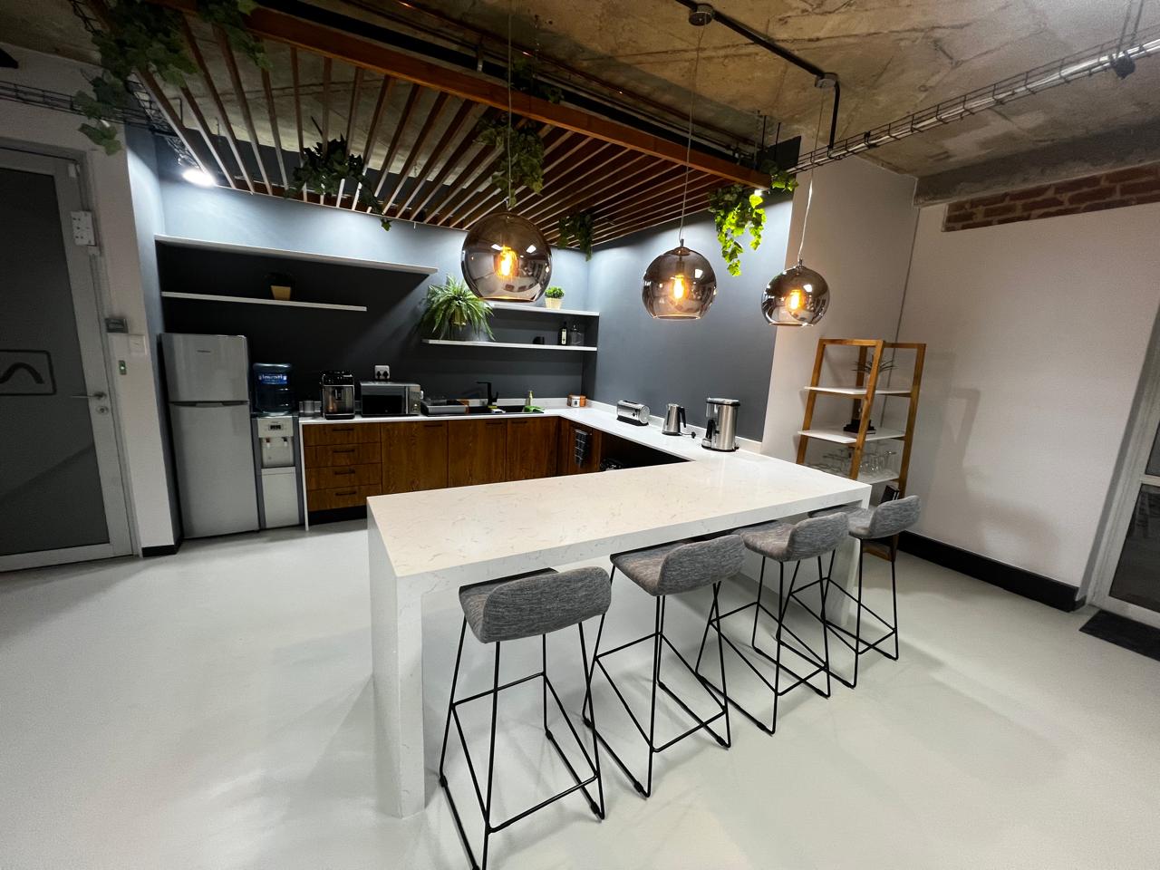 Industrial-style office kitchen with marble island and greenery, designed for staff comfort in Pretoria.